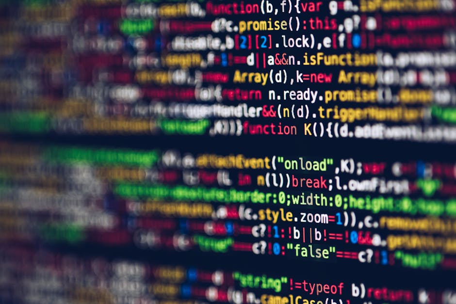 Photograph of a computer screen displaying a dense, colorful code editor filled with lines of programming language. The code is highlighted with various syntax colors including yellow, red, blue, gree